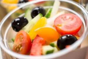 Close-up of a fresh vegetable salad with tomatoes, cucumber, olives, and peppers.