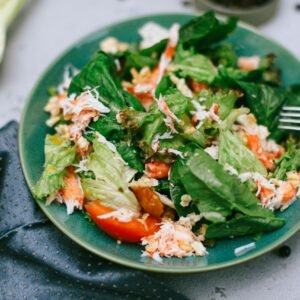 A vibrant green salad featuring mixed vegetables on a blue plate.