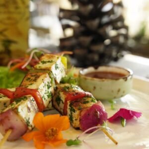 Close-up of grilled paneer and vegetable skewers with sauce, perfect for a gourmet meal.