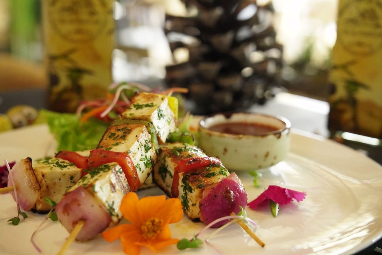 Close-up of grilled paneer and vegetable skewers with sauce, perfect for a gourmet meal.